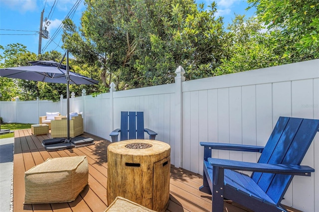 wooden deck featuring an outdoor fire pit and a fenced backyard