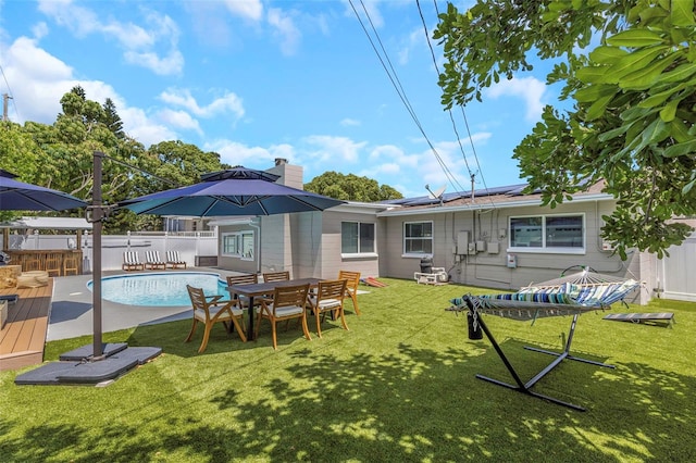 rear view of house with a fenced in pool, a yard, solar panels, and a fenced backyard