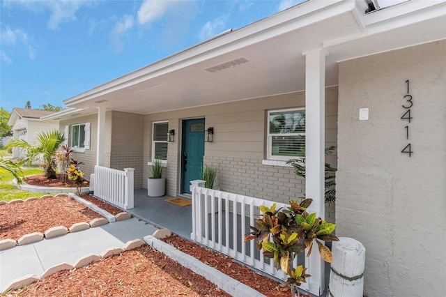 property entrance with brick siding and covered porch