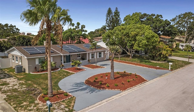 ranch-style home with driveway, solar panels, fence, a front yard, and central AC unit