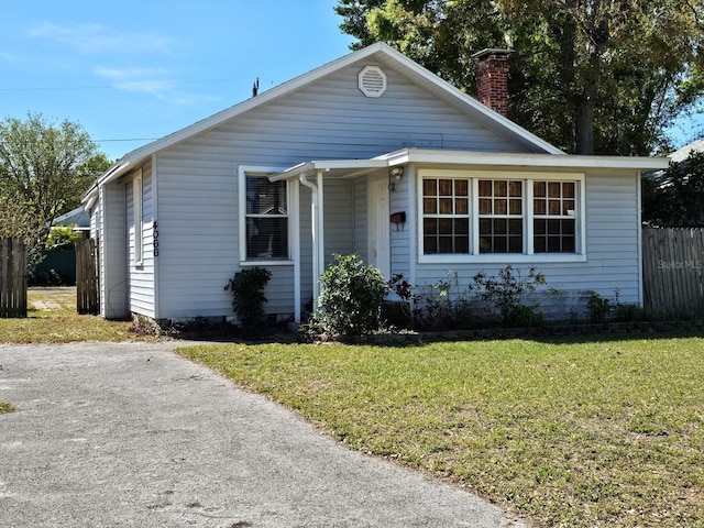 view of front of house featuring a chimney, a front yard, and fence