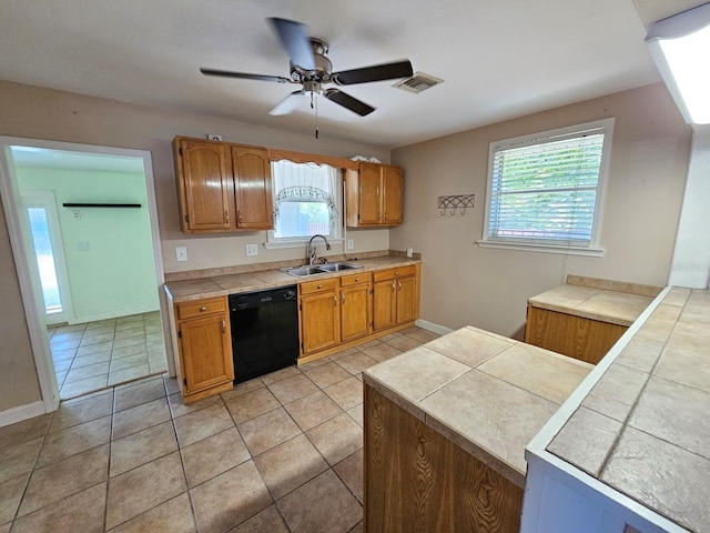 kitchen with visible vents, a ceiling fan, a sink, black dishwasher, and tile counters