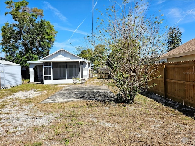 view of yard with a patio, a shed, a fenced backyard, a sunroom, and an outdoor structure