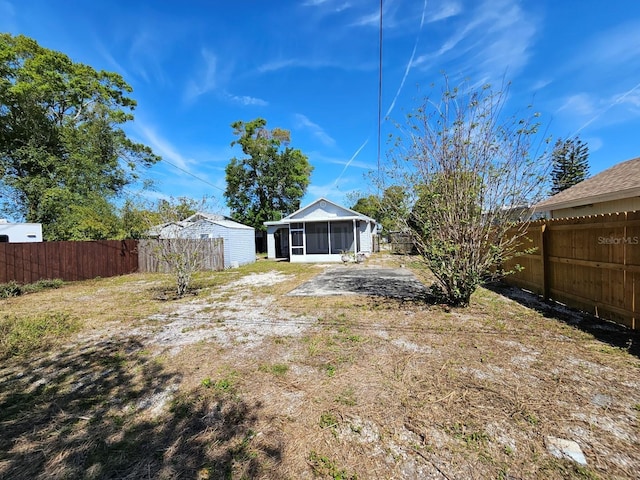 view of yard featuring a patio, a fenced backyard, and a sunroom