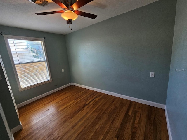 empty room featuring wood finished floors, baseboards, visible vents, and ceiling fan