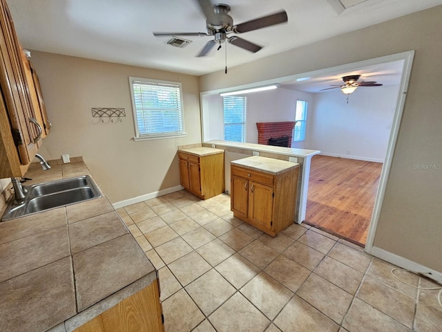 kitchen with light tile patterned floors, visible vents, a ceiling fan, and a sink