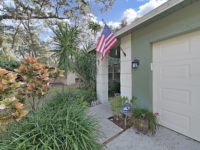 view of exterior entry with stucco siding and an attached garage