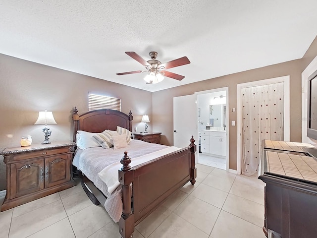 bedroom featuring ceiling fan, light tile patterned floors, ensuite bathroom, and a textured ceiling