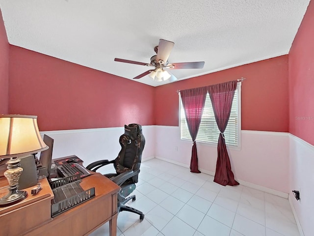 tiled office space featuring baseboards, a textured ceiling, and ceiling fan