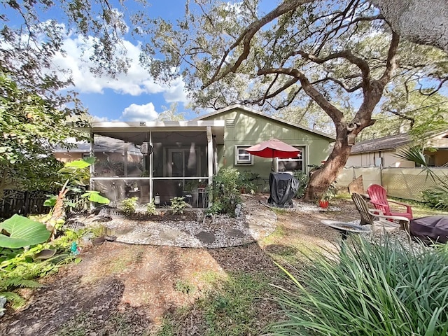 rear view of property featuring a sunroom and fence