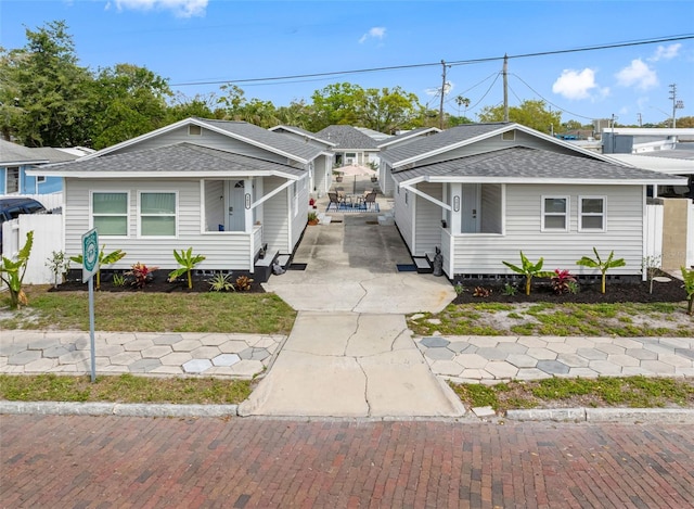 view of front of house featuring concrete driveway, roof with shingles, and fence