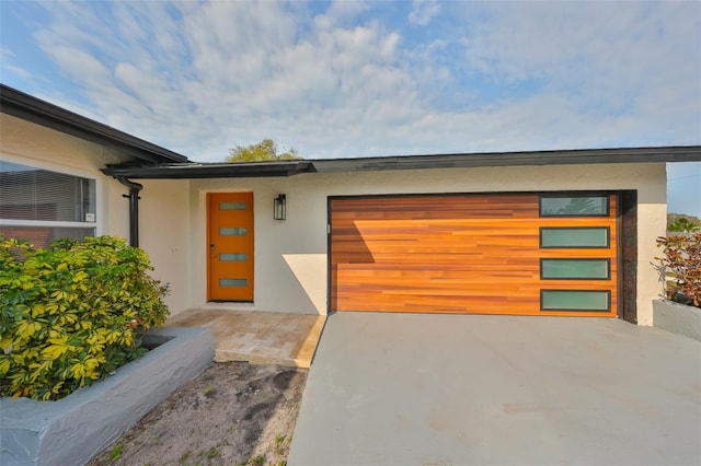 view of front of house with stucco siding, an attached garage, and driveway