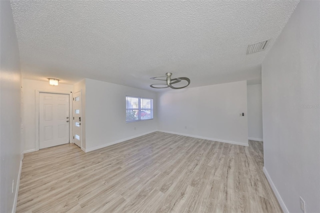 interior space featuring light wood-type flooring, visible vents, baseboards, and a textured ceiling