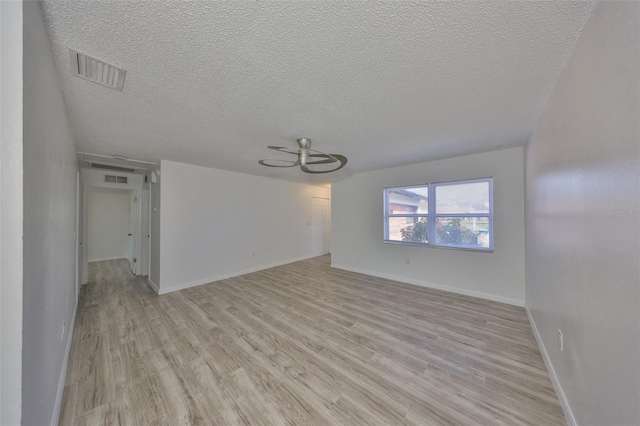 spare room with visible vents, baseboards, a textured ceiling, and light wood finished floors