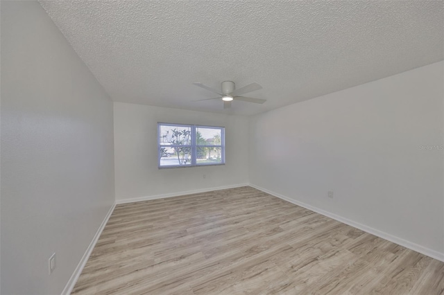 empty room with light wood-style flooring, a ceiling fan, baseboards, and a textured ceiling