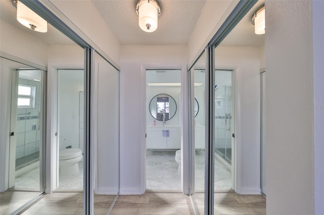 full bath featuring toilet, wood finished floors, and a textured ceiling