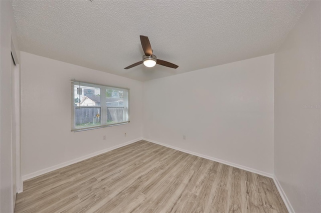 empty room with a textured ceiling, light wood-type flooring, baseboards, and a ceiling fan