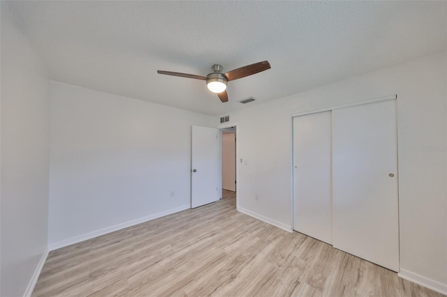 unfurnished bedroom featuring visible vents, baseboards, light wood-style flooring, a closet, and a textured ceiling