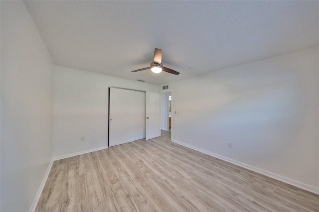 unfurnished bedroom featuring visible vents, baseboards, ceiling fan, light wood-style flooring, and a closet