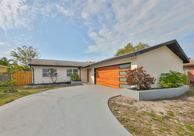 view of front facade with a garage, fence, driveway, and stucco siding