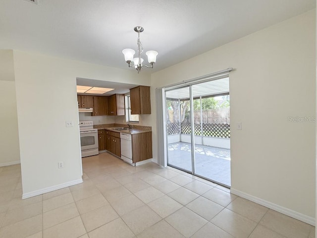 kitchen featuring under cabinet range hood, a sink, white appliances, an inviting chandelier, and baseboards