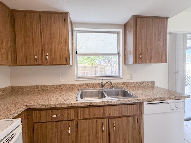 kitchen featuring brown cabinetry, white appliances, and a sink