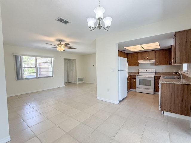 kitchen featuring visible vents, under cabinet range hood, open floor plan, white appliances, and a sink