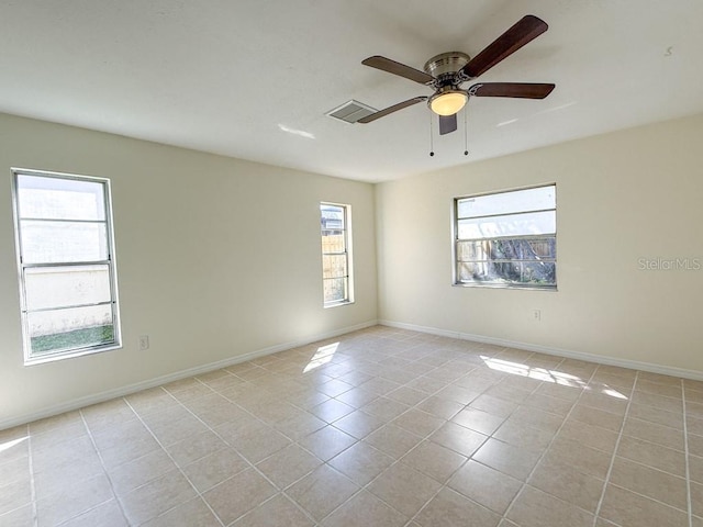 empty room with light tile patterned floors, baseboards, and a ceiling fan