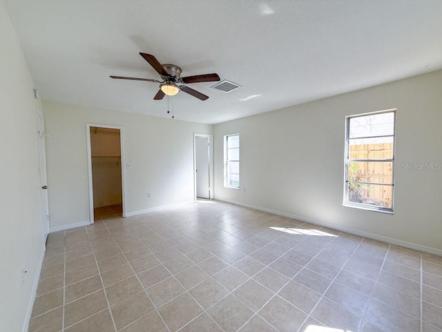 unfurnished room featuring light tile patterned flooring, a ceiling fan, visible vents, and baseboards