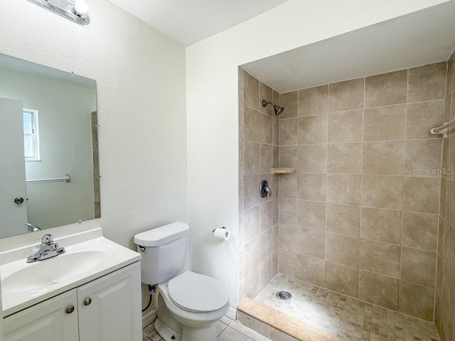 full bathroom featuring vanity, toilet, tile patterned flooring, and tiled shower