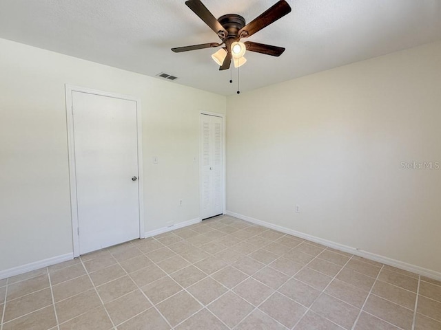 spare room featuring a ceiling fan, visible vents, and baseboards