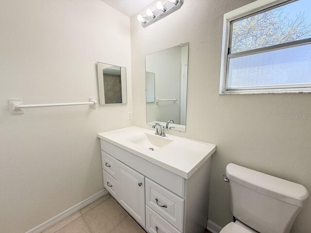 bathroom featuring vanity, toilet, baseboards, and tile patterned flooring