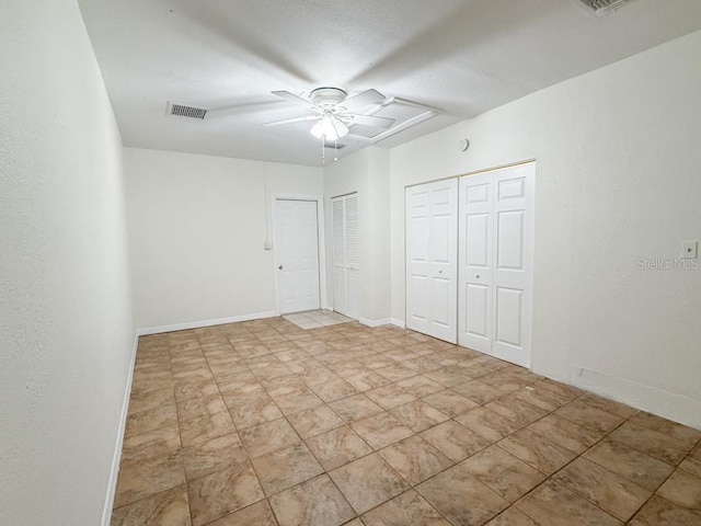 spare room featuring visible vents, baseboards, a textured wall, a textured ceiling, and a ceiling fan