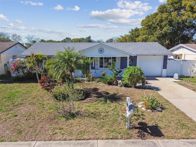 ranch-style home featuring an attached garage, concrete driveway, a front lawn, and fence