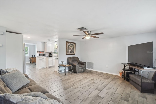 living room featuring visible vents, baseboards, light wood-style floors, and ceiling fan