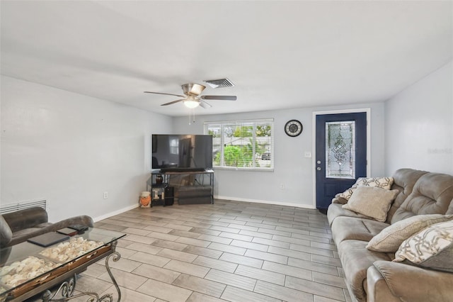 living room with visible vents, ceiling fan, and baseboards