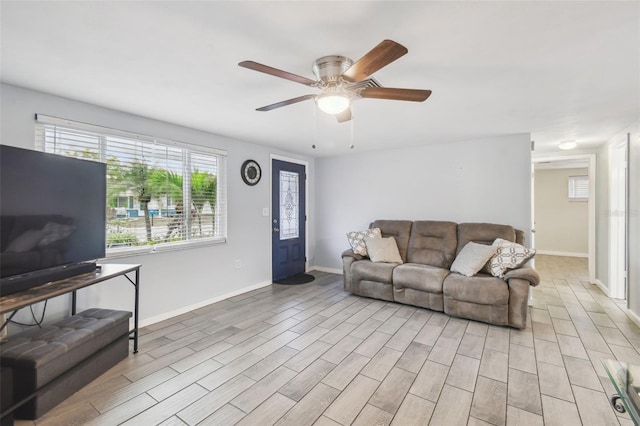 living area with light wood-type flooring, baseboards, and ceiling fan