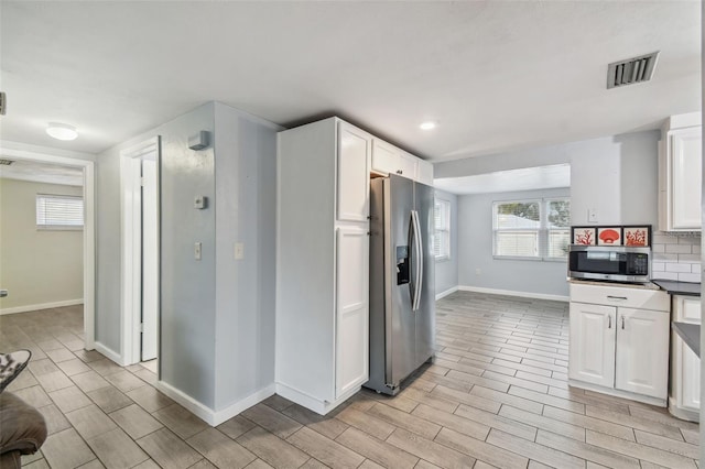 kitchen featuring tasteful backsplash, visible vents, appliances with stainless steel finishes, and white cabinetry