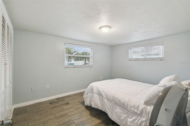 bedroom with a closet, baseboards, and wood finished floors