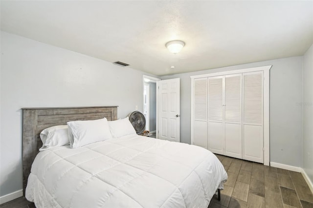 bedroom featuring a closet, visible vents, baseboards, and wood finished floors