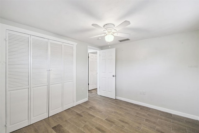 unfurnished bedroom featuring wood finished floors, visible vents, baseboards, ceiling fan, and a closet