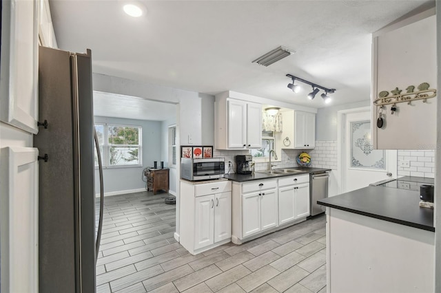 kitchen featuring dark countertops, white cabinets, tasteful backsplash, and appliances with stainless steel finishes