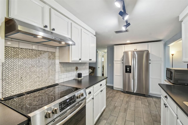 kitchen with visible vents, under cabinet range hood, tasteful backsplash, dark countertops, and appliances with stainless steel finishes