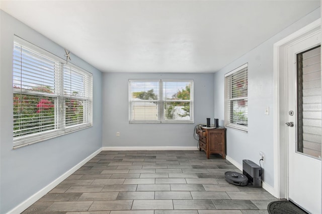 empty room with wood finish floors, a healthy amount of sunlight, and baseboards