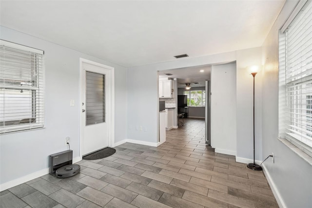 empty room featuring ceiling fan, visible vents, baseboards, and wood finished floors