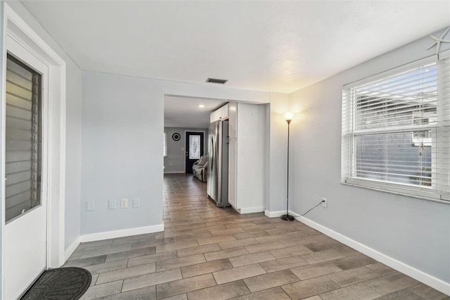 corridor featuring wood finished floors, visible vents, and baseboards