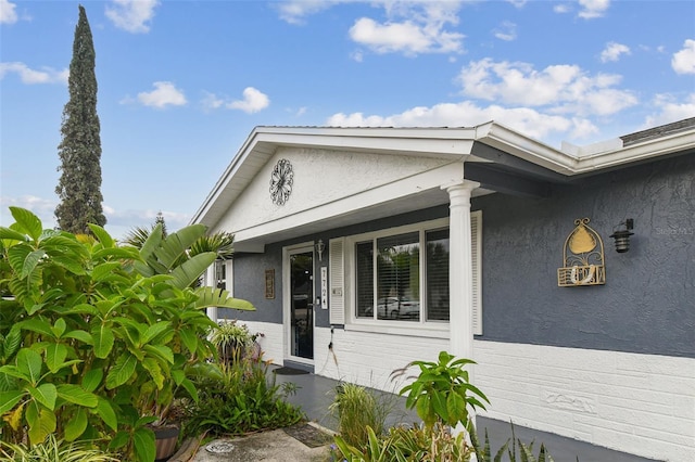 view of exterior entry featuring stucco siding and a porch