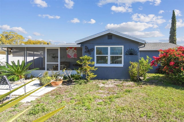 view of front of property with stucco siding, a front lawn, and a sunroom