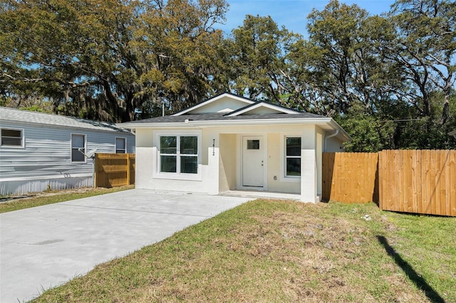 view of front of property with stucco siding, a front yard, and fence