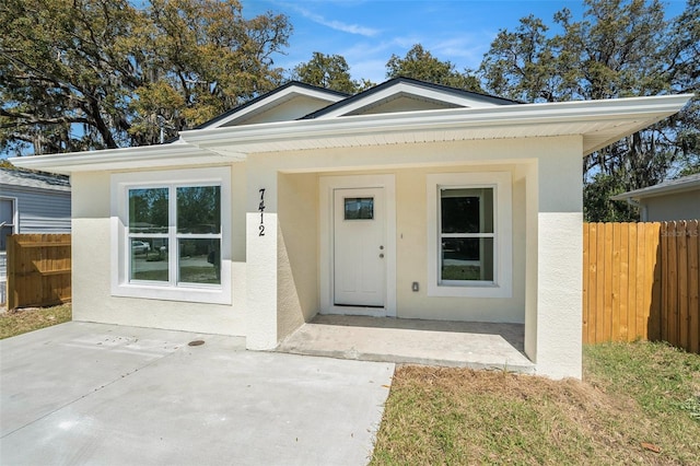 view of front of house with stucco siding and fence